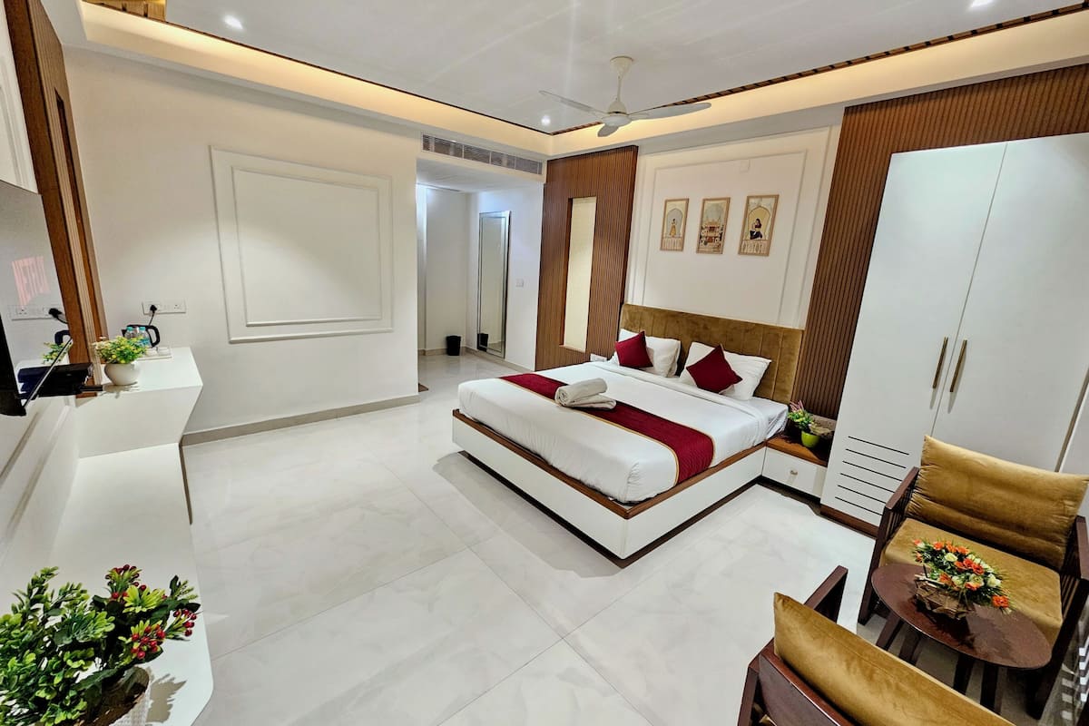 A modern hotel room with a bed, a desk, a chair, and a wardrobe.