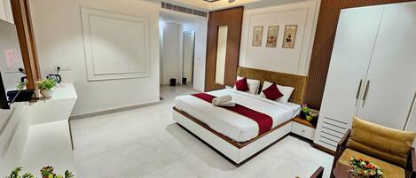A modern hotel room with a bed, a desk, a chair, and a wardrobe.