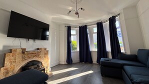 A living room with a fireplace, a flat-screen TV, a sofa, and a ceiling fan. - Tranquil Hideaway w/Hot Tub and Pool Table (Cardiff)