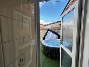 Pihalla sijaitseva poreallas, jonka takana on laatoitettu seinä ja siinä on ikkuna.