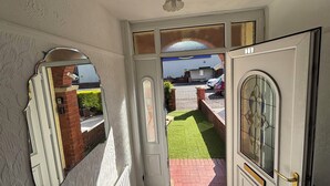 A hallway with a white door, a mirror, and a view of a garden and a building outside. - Tranquil Hideaway w/Hot Tub and Pool Table (Cardiff)