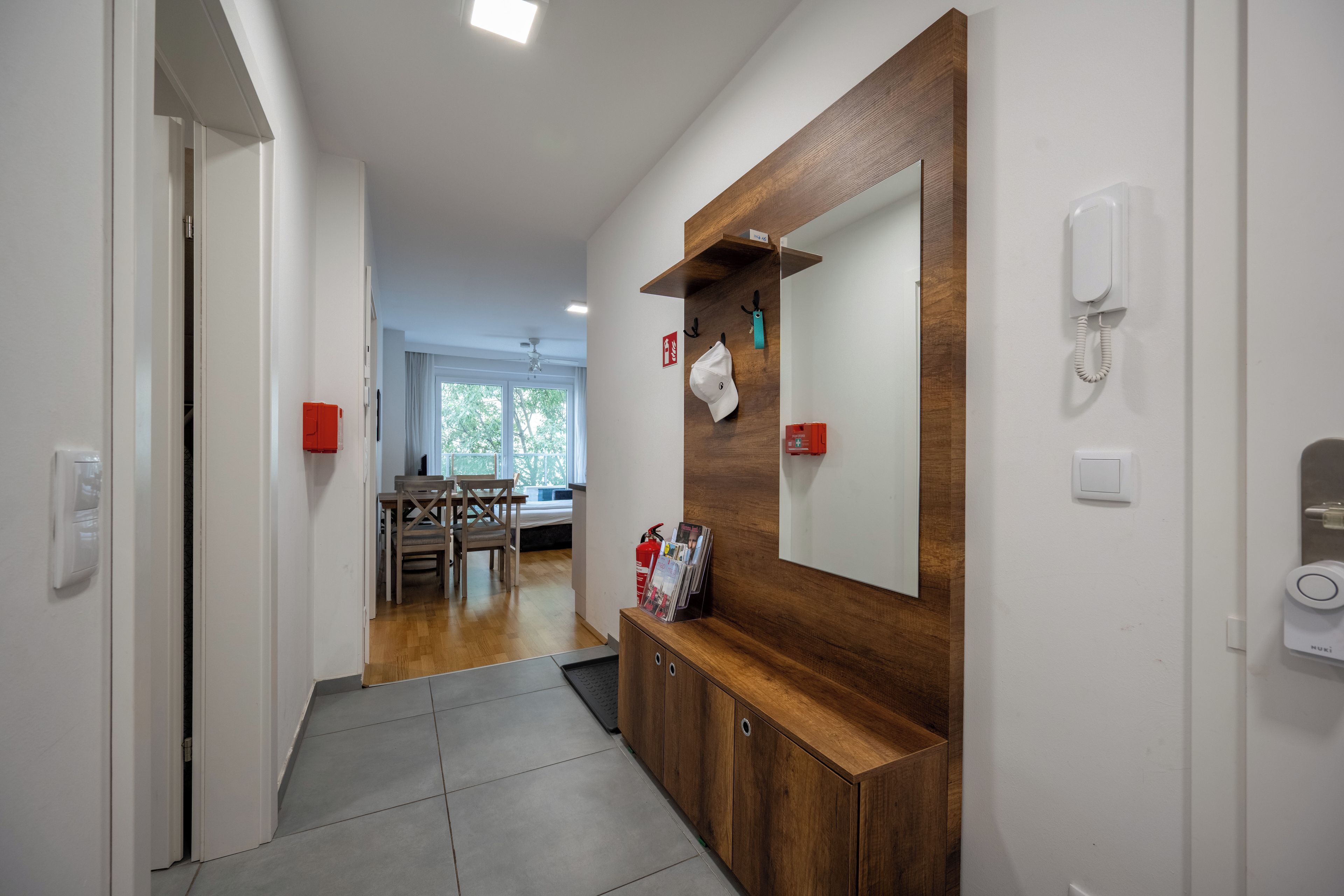 A hallway with a wooden cabinet, a mirror, and a telephone.