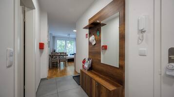A hallway with a wooden cabinet, a mirror, and a telephone.
