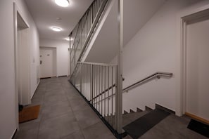 Una escalera moderna con barandillas y pasamanos de metal que conduce a una puerta con un cartel en la parte superior.