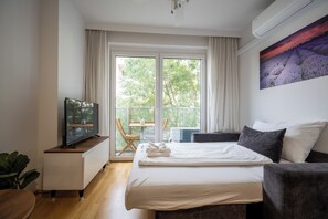 A modern hotel room with a bed, a TV, a small table, and a chair by the window. - Moderne & ruhige Apartments in Wien (Vienna)