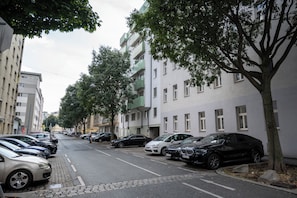 Una calle bordeada de vehículos estacionados y edificios de varios pisos.