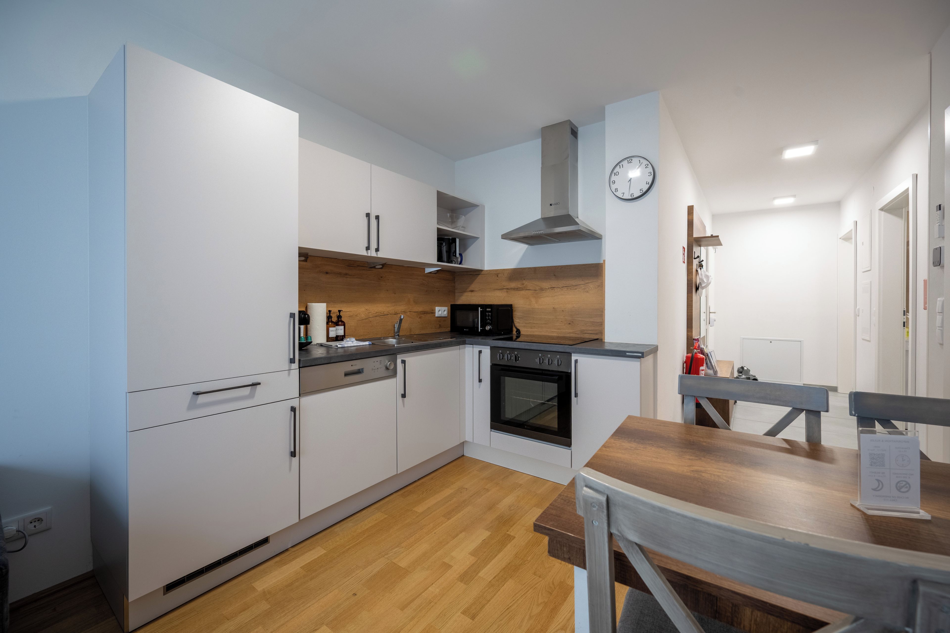 Een moderne keuken met witte kastjes, een houten aanrecht, een inbouwoven en een magnetron.