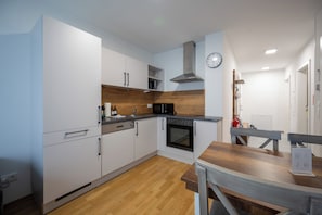 A modern kitchen with white cabinets, a wooden countertop, a built-in oven, and a microwave. - Moderne & ruhige Apartments in Wien (Vienna)