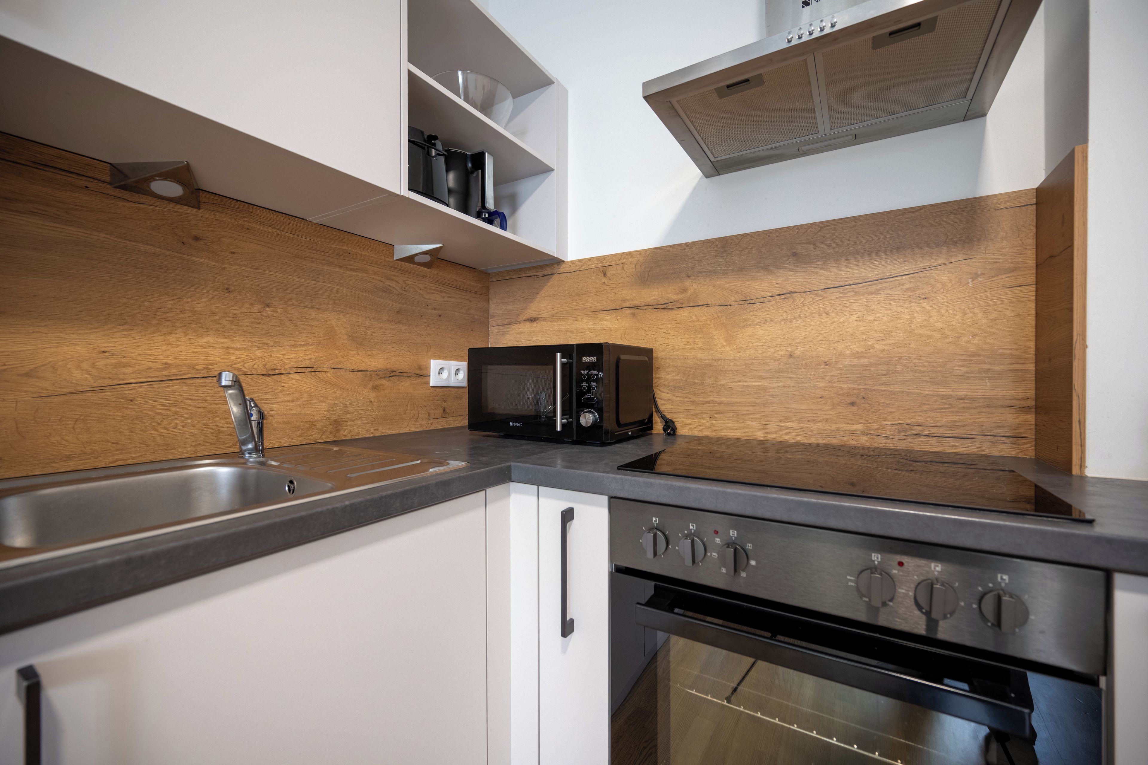 A modern kitchen with a built-in microwave, stainless steel sink, and a double oven.