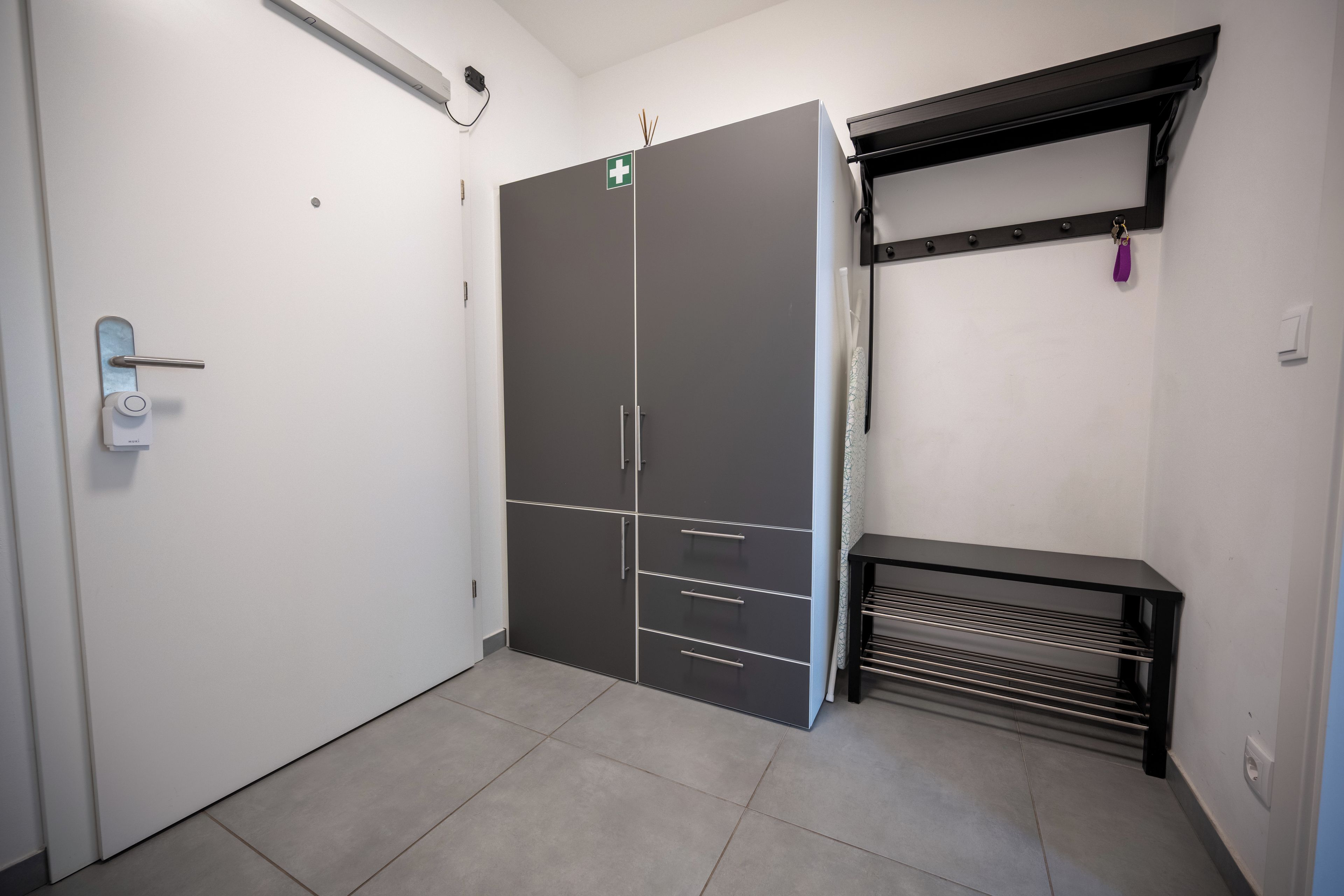 Een kamer met een inbouwkast, een deur, een plank en een betegelde vloer.