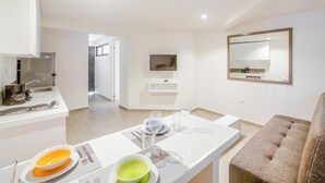 A modern kitchen with a dining area, a TV mounted on the wall, and a sofa in the living room. - Air, King Bed, Kitchen, 50 Mbps Wi-Fi, V1 (Playa del Carmen - Valentina Suites)