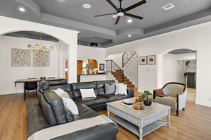 A living room with a black leather sofa, a coffee table, and a staircase. - Central Austin Retreat w/ Pool (Austin)