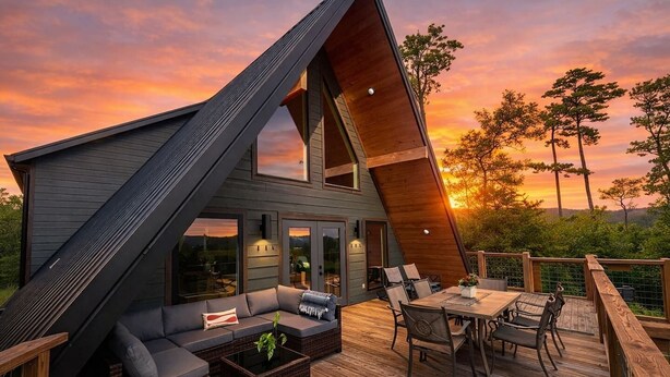 A modern house with a sloped roof, a deck with outdoor furniture, and a view of the sunset. - Starfall A-Frame Hot tub + View + Firepit (Jasper)