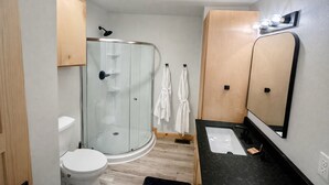 A modern bathroom with a glass shower enclosure, a toilet, a sink, and a mirror. - Starfall A-Frame Hot tub + View + Firepit (Jasper)