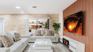Ein modernes Wohnzimmer mit einer Couch, einem Couchtisch und einem an einer Holzwand befestigten Flachbildfernseher.