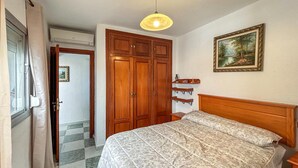 A bedroom with a bed, wooden wardrobe, a painting, and a ceiling light. - 2 bedroom amazing apartment in Marbella (Marbella)