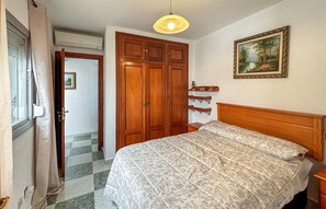 A bedroom with a bed, wooden wardrobe, a painting, and a ceiling light. - 2 bedroom amazing apartment in Marbella (Marbella)