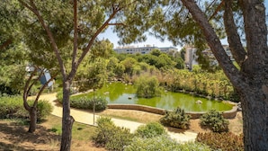 A park with a pond, trees, and a building in the background. - 2 bedroom amazing apartment in Marbella (Marbella)
