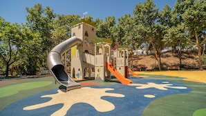 A playground with a slide, climbing structures, and a castle-like playhouse. - 2 bedroom amazing apartment in Marbella (Marbella)