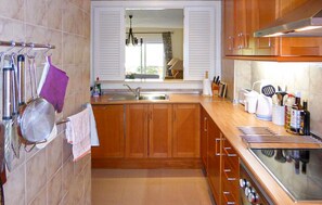 A kitchen with wooden cabinets, a stainless steel sink, and a stove. - Nice home in Mijas with WiFi (Mijas)