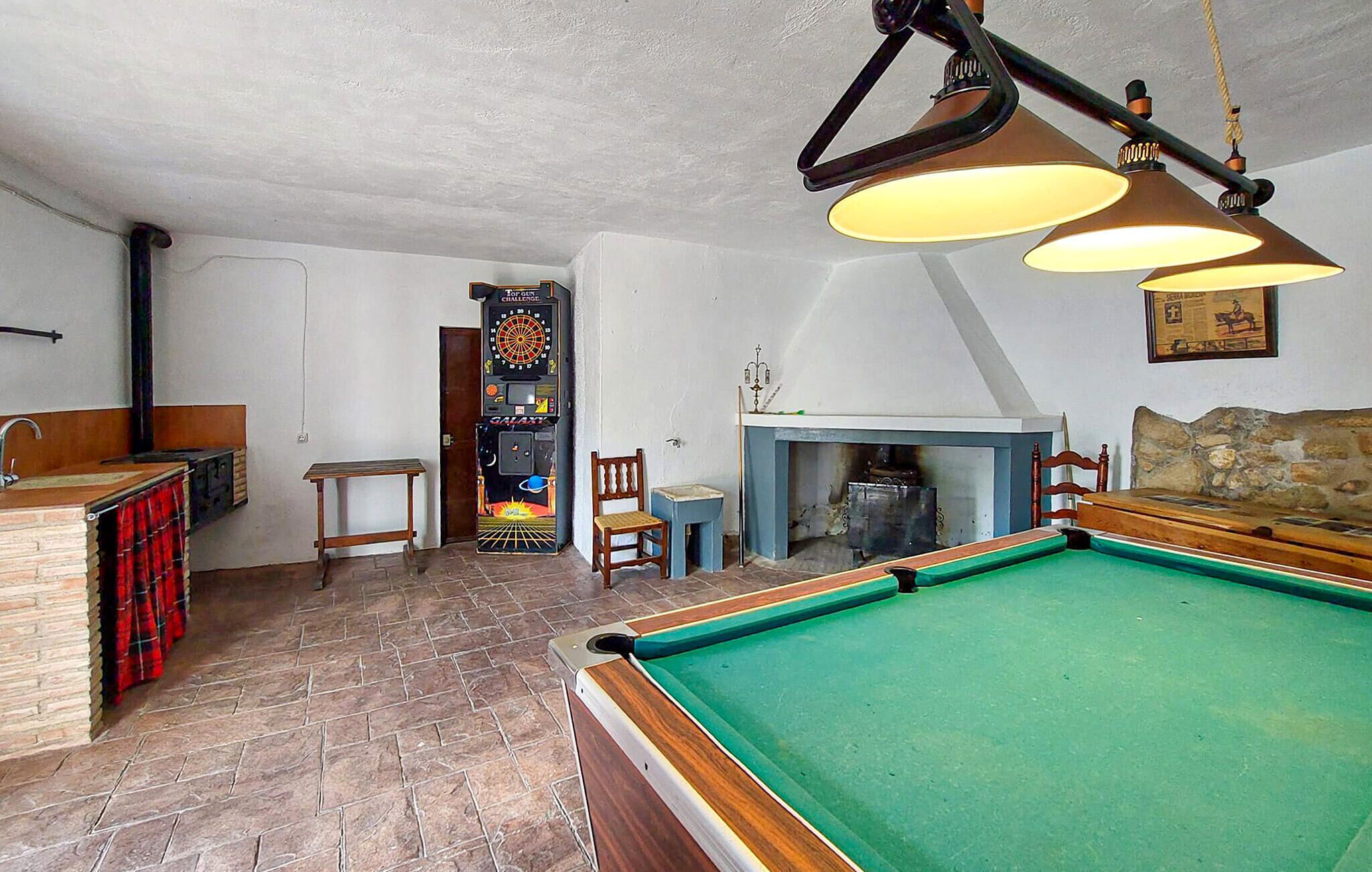Een pooltafel in een ruimte met een dartbord, een open haard en een bar.