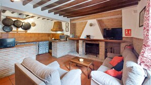 Ein modernes Wohnzimmer mit Kamin, Küchenbereich mit Ziegelrückwand und Fernseher.
