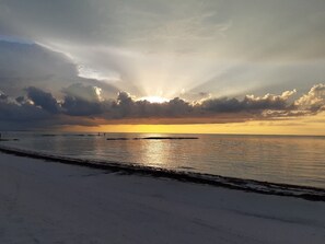 A beach with a sunset, calm sea, and a distant pier. - Kitchenette,Sleeps 4, Beach 1 Block, Starlink, c5 (Isla Holbox)