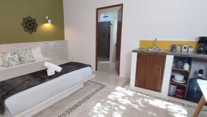Een slaapkamer met een bed, een nachtkastje, een kledingkast en een deur naar de badkamer.