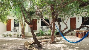 Un pati amb cadira d'èmfases, arbres, taula de fusta i mobiliari exterior.