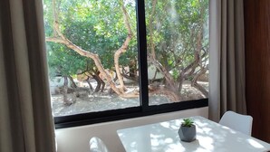 Una habitació amb una finestra, una taula amb una planta i un llit amb capçalera de fusta.