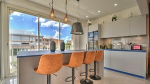 A modern kitchen with a large island, bar stools, and pendant lighting. - Apartment TalyJay - 2 bedrooms with swimming pools (Nettle Bay)