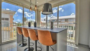 A modern kitchen with a bar area, large windows, and a view of the neighborhood. - Apartment TalyJay - 2 bedrooms with swimming pools (Nettle Bay)
