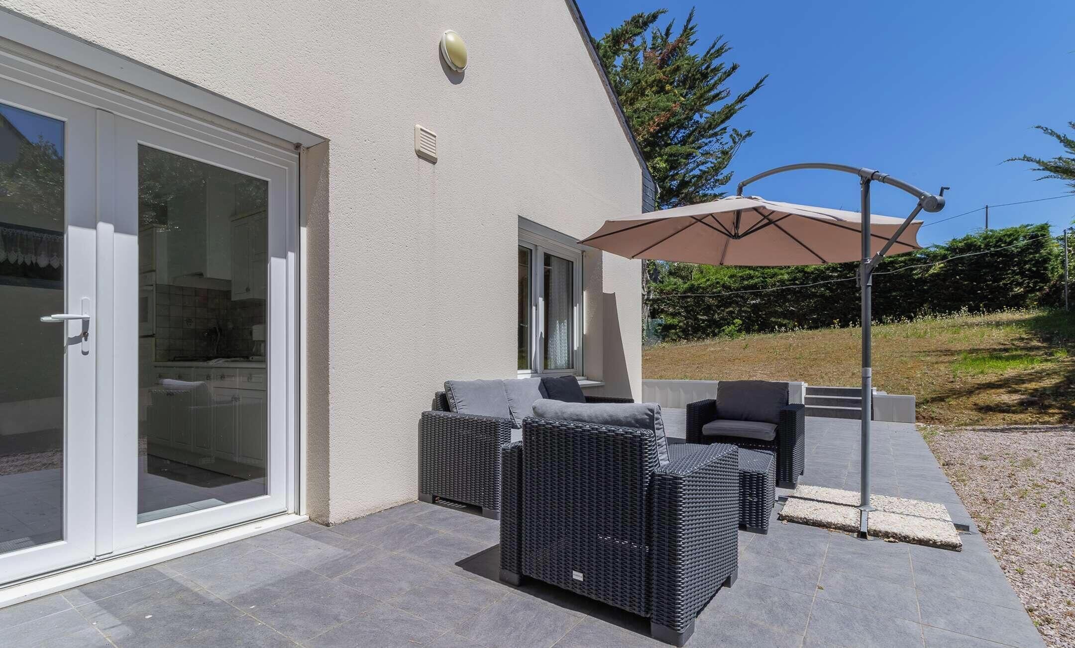 An outdoor patio with wicker furniture and a large umbrella.