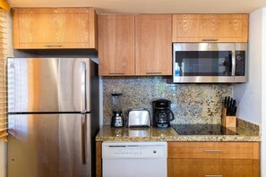 Una cocina compacta con electrodomésticos de acero inoxidable, armarios de madera y encimera de granito.
