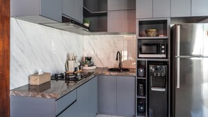 Una cocina moderna con un refrigerador de acero inoxidable, un microondas integrado y un dispensador de agua.