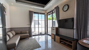 Una sala de estar moderna con un sofá, televisión y un ventanal grande.