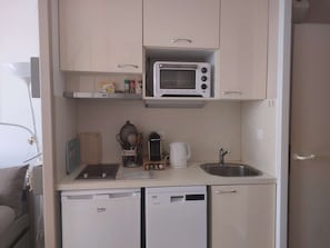 Eine kleine Küchenzeile mit Mikrowelle, Kaffeemaschine, Spüle und Geschirrspüler.