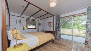 Een slaapkamer met een bed, een bureau, een lamp, een raam en uitzicht op de omgeving.