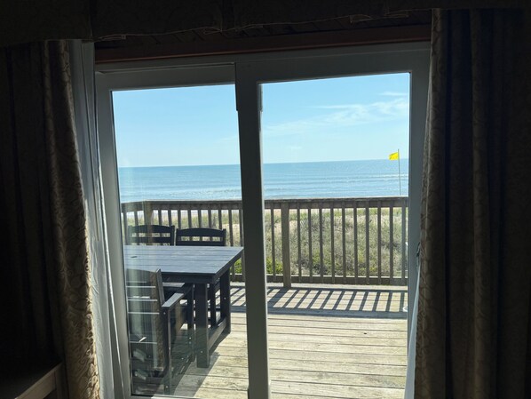 Vista de um quarto com porta de vidro deslizante para um deck de madeira com vista para o oceano.