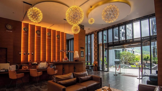 A modern lobby with a reception desk, leather seating, and large windows offering a view of the outdoors. - Modern 1-bedroom Suite With Pool Access in Kamala, Phuket (Kamala)
