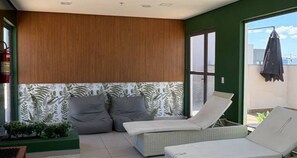 A balcony with two lounge chairs, a wooden ceiling, and a patterned wall. - Studio with Sea View | Ocean View Studio with Pool, WiFi & AC (Rio de Janeiro)