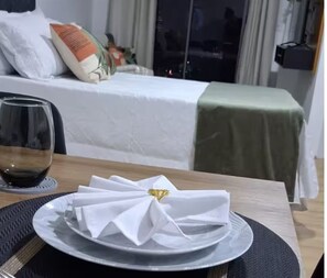 A neatly arranged dining table with a folded white napkin, a clear glass of red wine, and a plate on a placemat. - Studio with Sea View | Ocean View Studio with Pool, WiFi & AC (Rio de Janeiro)