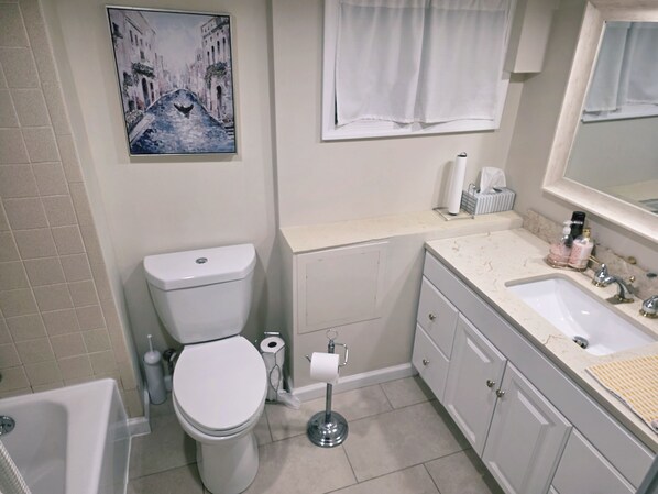 Un baño con inodoro, lavabo y un cuadro de una escena de canal.