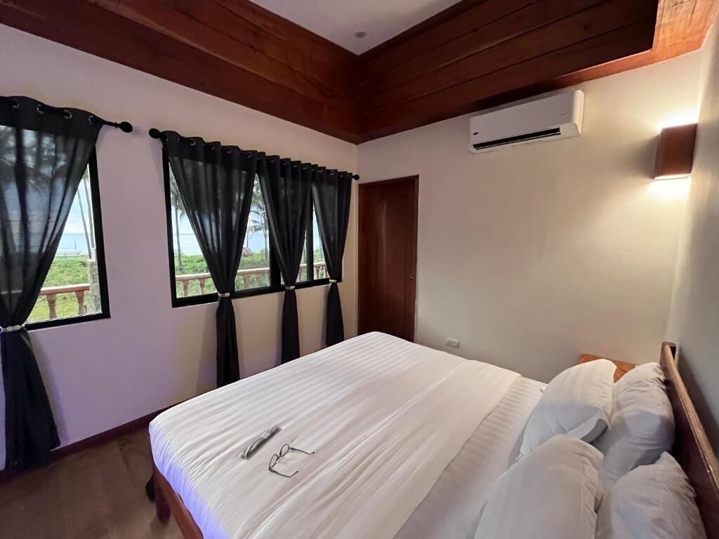 Ein Schlafzimmer mit Bett, Vorhängen, einer Klimaanlage und Blick ins Freie.