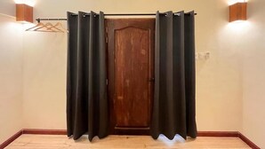 Una habitación con puerta de madera, cortinas negras y luces fijadas a la pared.