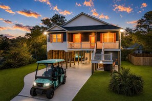 Une maison à deux étages dotée d’un patio couvert, d’une voiturette de golf et d’une pelouse bien entretenue.