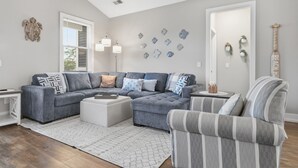 Una sala de estar con un sofá modular, un sillón a rayas, una mesita auxiliar y decoración en la pared.