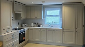 A modern kitchen with grey cabinets, a built-in oven, and a window providing natural light. - Derry City Apartment (walking distance to city centre and local amenities) (Londonderry)