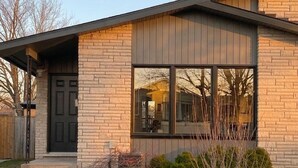 Ein modernes Haus mit Ziegelaußenwand, großen Fenstern und einem gepflegten Rasen.