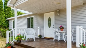 A house with a porch, white railings, and steps leading to the entrance. - Private Retreat Near Interlochen Arts| Green Lake (Interlochen)